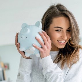 Junge Frau mit Sparschein in den Händen, ans Ohr haltend