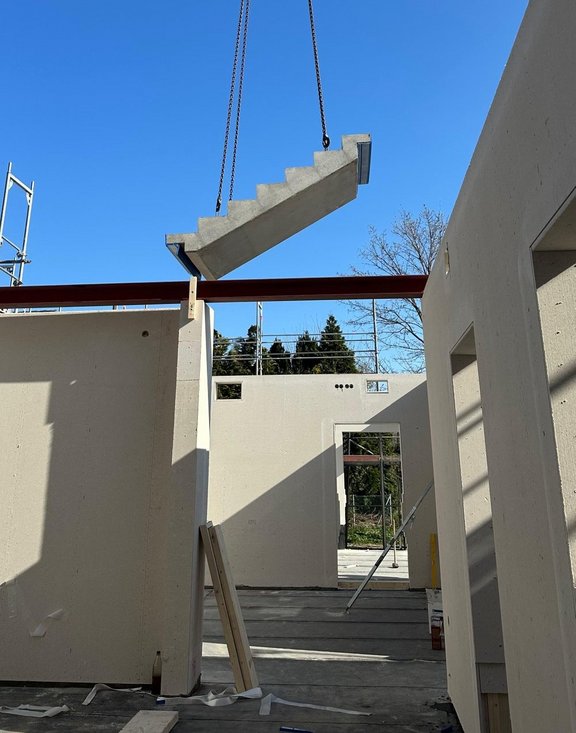 Bein Bauteil schwebt am Kran in den Rohbau