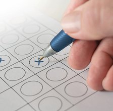 Hand mit Kugelschreiber kreuzt einen Wahlzettel an