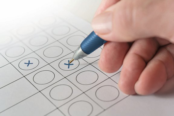 Hand mit Kugelschreiber kreuzt einen Wahlzettel an