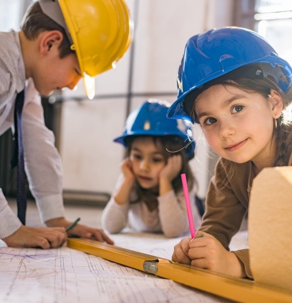 Drei kleine Kinder mit Bauhelmen spielen