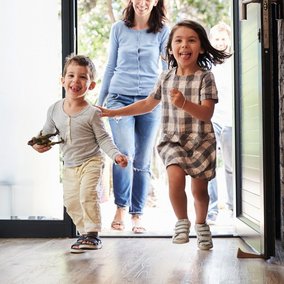 Mutter mit zwei kleinen Kindern kommt in den Hausflur