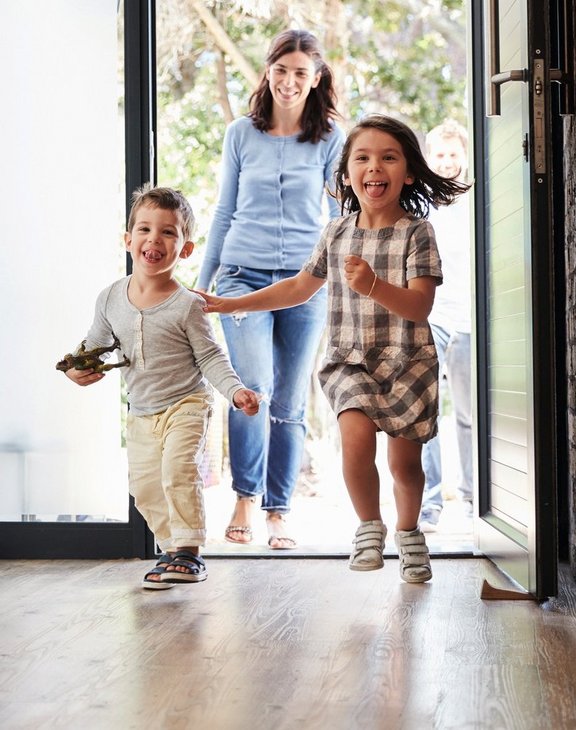 Mutter mit zwei kleinen Kindern kommt in den Hausflur